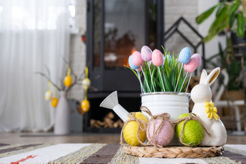 Easter decor near fireplace stove with fire and firewood. Cozy home hearth in interior with potted plans, colorful easter eggs, easter bunny and bouquet. Spring in a country house