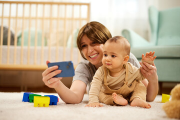 A mother taking a selfie with her baby boy at home