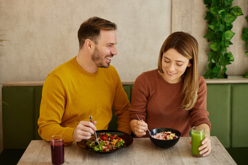Mid adult couple enjoy eating salads and drinking smoothies in salad bar