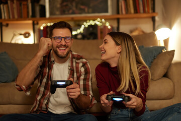Young couple having fun at home playing video games