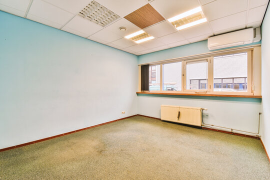 an empty room with blue walls and white trim on the ceiling, there is a small window in the corner