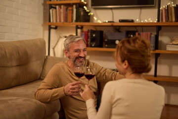 Romantic mature couple relaxing at home and drinking red wine