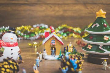Creative concept with miniature people creating Christmas decorations on a wooden background.