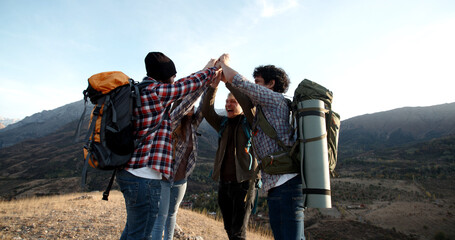 Students on hike adventure - Four young authentic people cheering on top of mountain, doing a...