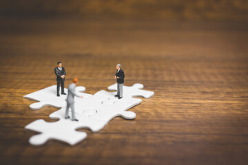 Miniature people: Businessman standing on jigsaw