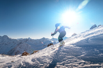 young female skier quickly descends the slope in the alpine mountains. Winter sports and...
