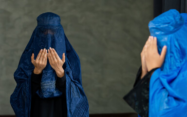 Portrait selective focus adult Muslim woman wearing headscarf, traditional dress, hiding face, praying with hope, wishes. Diversity, Religious Concept.