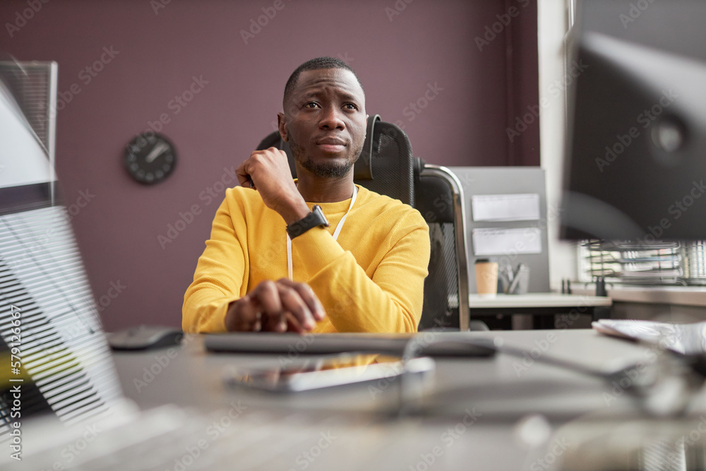 Poster low angle portrait of focused black man using computer in it development office, copy space