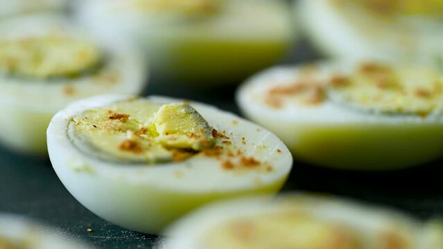 Woman hand adding spices on the boiled egg. Closeup macro shot in 4K.