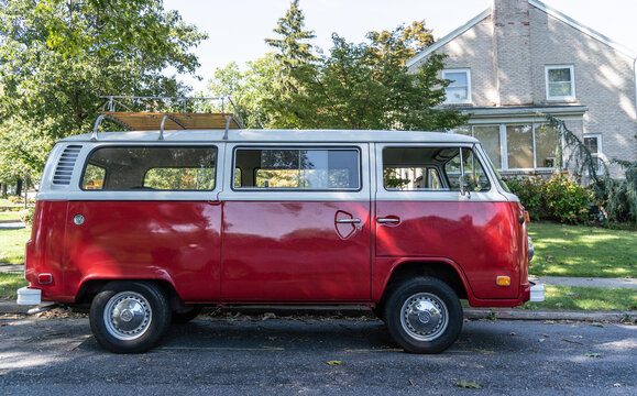 Red Volkswagen Van side-view parked on suburban street. 