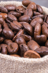 Heap of dark roasted fragrant coffee beans in jute bag
