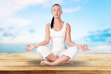 Relaxed young woman practices yoga on sea background
