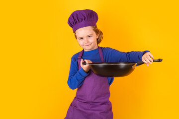 Kid boy chef cook with cooking pan. Chef kid boy making healthy food. Portrait of little child in chef hat isolated on studio background. Child chef. Cooking process.