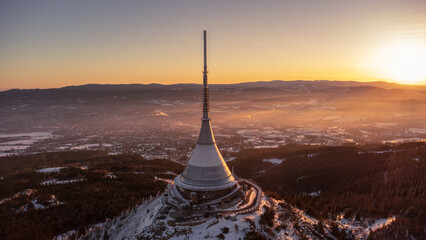 A bird's eye view of snow-covered Jested at sunrise. Photographed on the Jested ridge by drone. Beautiful winter landscape in Liberec region.