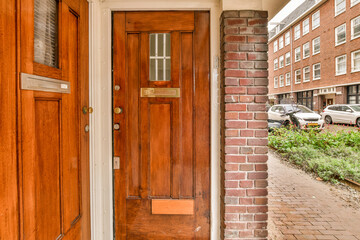a wooden door in front of a brick building with a car parked on the side walk way next to it