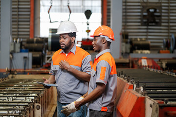 factory engineer is walking around inspecting machines inside a factory with a factory mechanic.