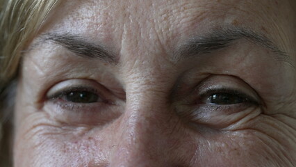 Senior woman opening eyes macro closeup. Portrait face detail of mature female person eye smiling with wrinkles