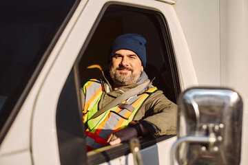 Smiling professional driver driving his truck and looking at camera.