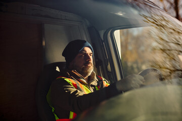 Mid adult driver behind steering wheel of truck.