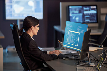 Side view portrait of female IT developer using computer at workplace in high tech office