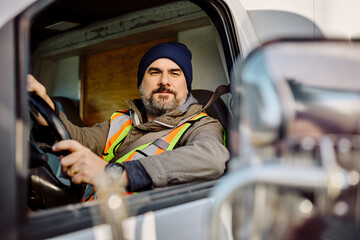 Truck driver using side mirror while driving in reverse.