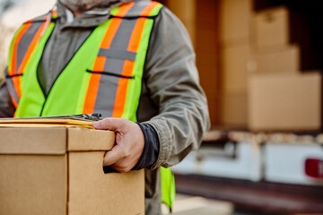 Close up of courier taking cardboard boxes out of delivery van.