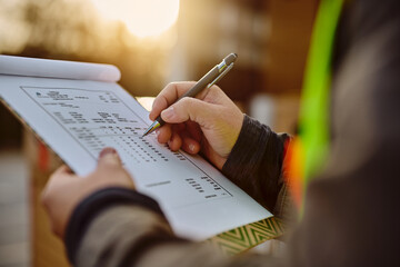 Close up of truck driver takes notes while going through delivery list.
