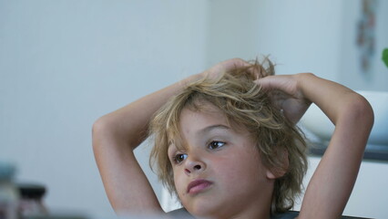 Fototapeta premium One thoughtful young boy playing with hair while dreaming. A pensive kid lost in thought spacing out. Child with contemplative expression