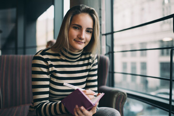 Smiling woman sitting with notebook in cafe