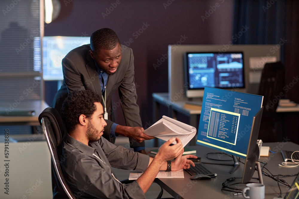 Poster two male it engineers discussing documentation at workplace in office and reviewing code
