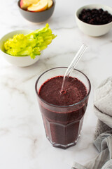 Healthy breakfast, frozen blueberry, avocado and banana smoothie, pea protein and flax seeds, lettuce and celery, apple, smoothie in a glass with a straw