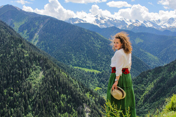 Elegant woman at the mountains. Happy girl with wavy hair. Freedom concept. The background of the majestic mountains of the Caucasus and wooden fence. Svaneti, Georgia.