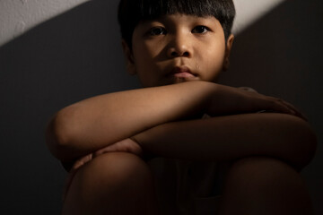 Portrait of a asian kid sitting alone and looking at the camera. Homesick or sadness or broken...