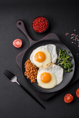 Delicious hearty breakfast consisting of two fried eggs, canned lentils and microgreens