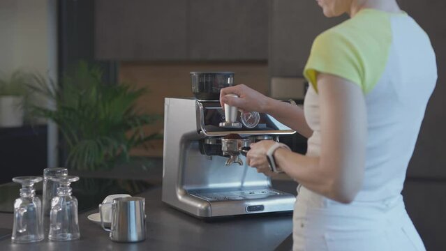 Caucasian female is filling the portafilter with espresso powder