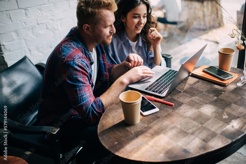 Poster skilled male and female programmers talking during collaborative software developing in coffee shop,