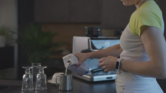 Caucasian female is pouring milk into milk jug.