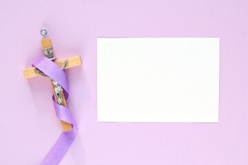 Christian religious wooden cross crucifix with violet ribbon on purple background. Catholic...