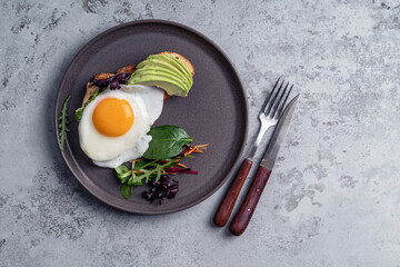 Breakfast with toasted bread, sliced avocado, and fried egg, directly above