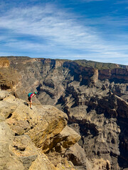 Kobieta schodząca ze skały w kanionie Jabal Shams w Omanie - obrazy, fototapety, plakaty