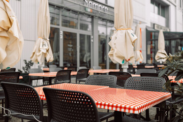 Empty wet wooden table and chairs on terrace of outdoor cafeteria during rain. Street city life in rain. Gdansk, Poland