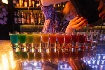 Dozen of colorful rainbow cocktails being prepared on the counter by a bartender in Gdansk, Poland