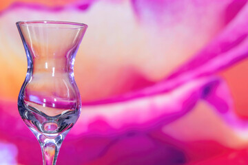 Close up of empty clear liqueur glass against a magenta background, nobody