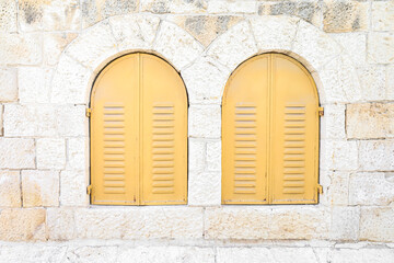 Fototapeta na wymiar View of old building with yellow window shutters