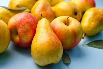 Heap of fresh pears and apples on blue background, closeup