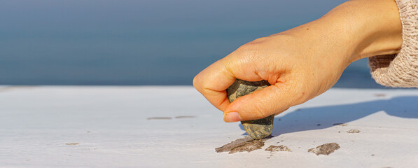 Someone scraping wooden table with stone. High resolution photo image can be used as large printed canvas, website banner, social media post. Copy space for advertising.
