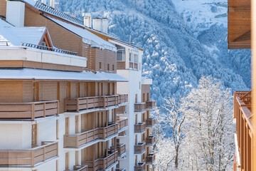 ski resort condominium with wooden elements in winter landscape with mountains covered by snow and frost