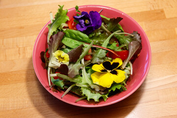 Beautiful mix salad with flowers on a wooden table. Diet concept. Healthy vegan food