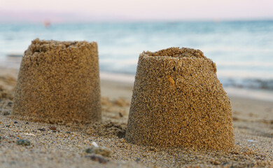 Sand castle on beach at summer vacation by the blue sea. Child having fun on holiday concept idea.