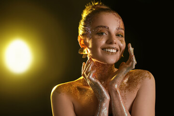 Beautiful young woman with glitter makeup on dark background, closeup